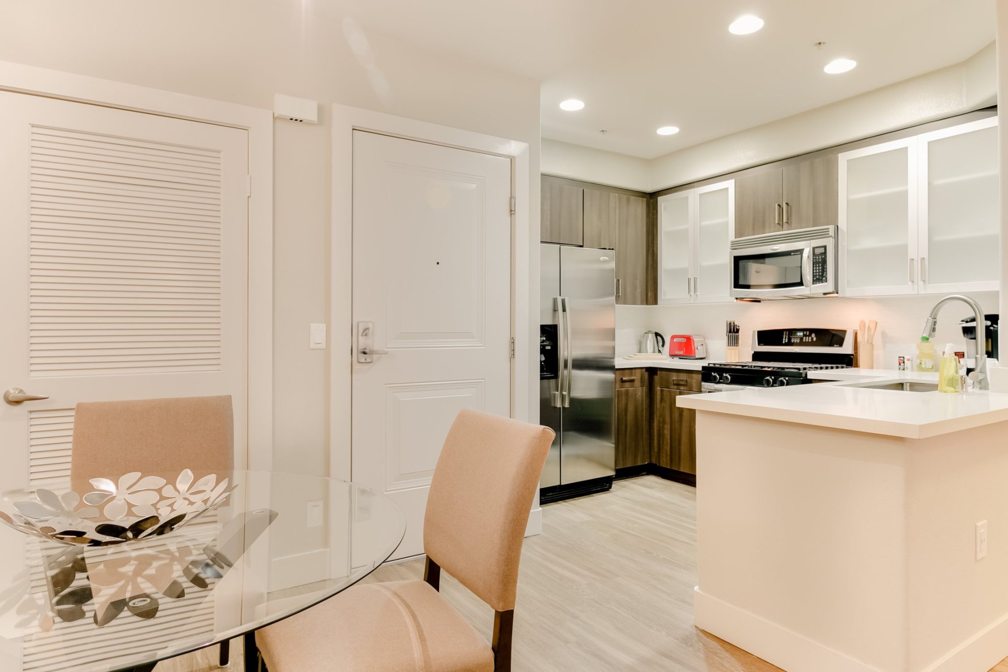 Fully furnished living room with an open kitchen layout in a Los Angeles Luxury Furnished Housing apartment, featuring modern furniture, appliances, and décor.