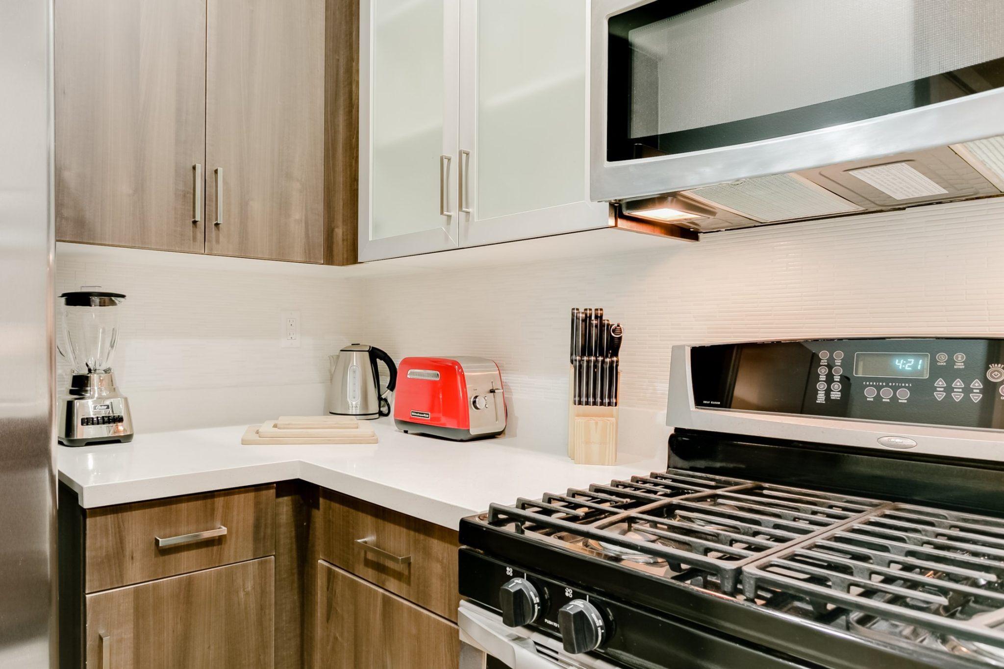 Modern, fully equipped kitchen in a Los Angeles Luxury Furnished Housing apartment, featuring stainless steel appliances, countertops, and cookware.