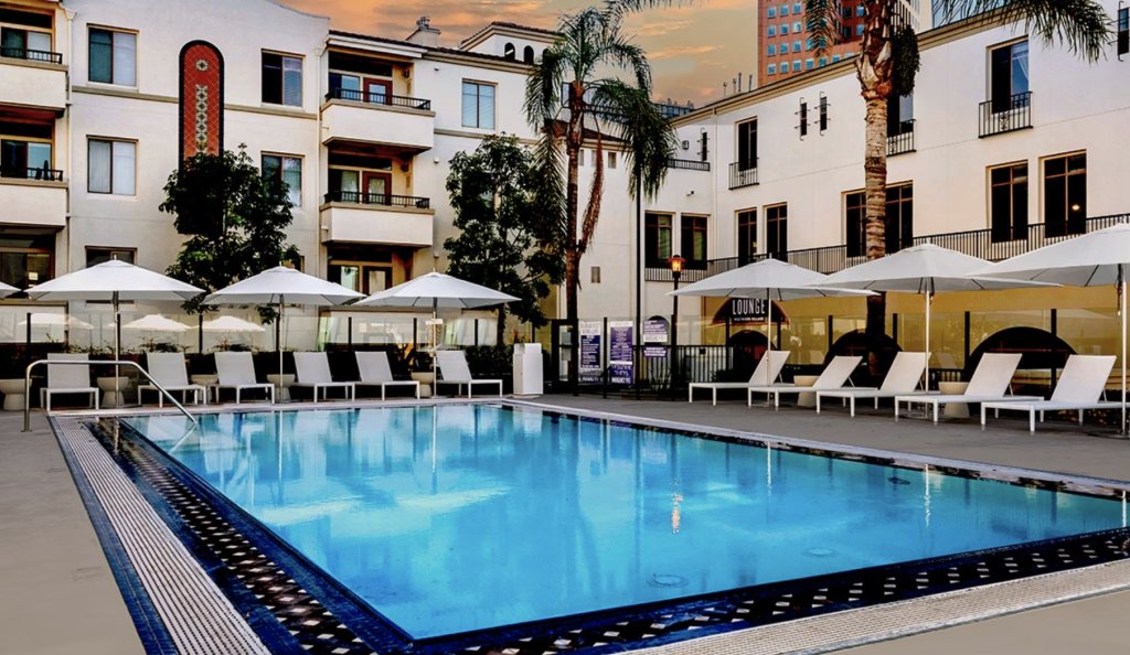 Resort-style swimming pool at The Glendon Apartments in Westwood, Los Angeles, offered by Los Angeles Luxury Furnished Housing with lounge chairs and palm-lined deck.